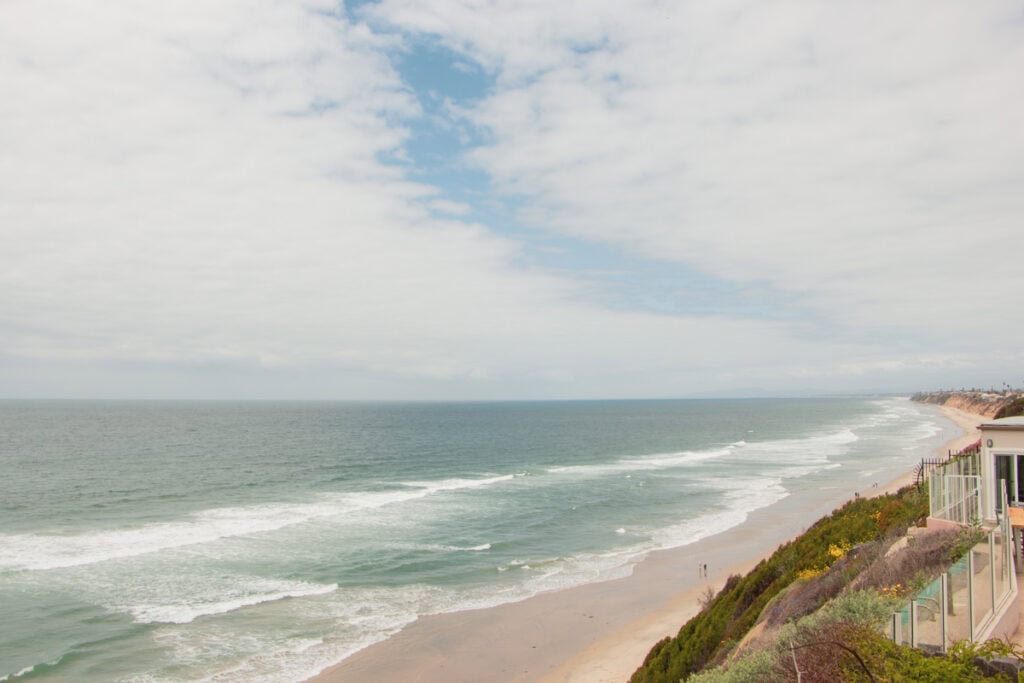 View of Moonlight Beach from the I Street Viewpoint in Encinitas. The beach is below, and there is a home on the coastal cliff on the right.