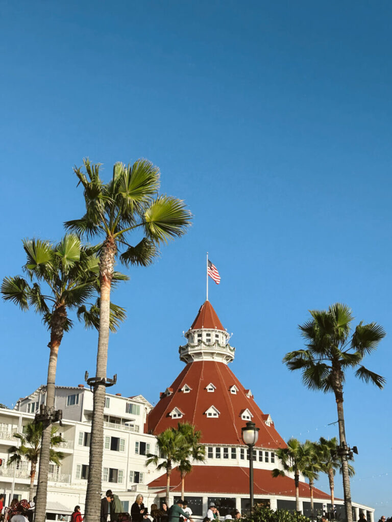 The orange tiled roof of Hotel del Coronado, with palm trees on either side. 