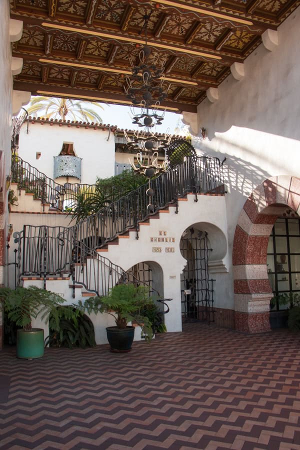 The entryway to El Andaluz by Jeff Shelton. Stairs zig-zag up to a second outdoor level, and there is a chandelier hanging over the entry space.