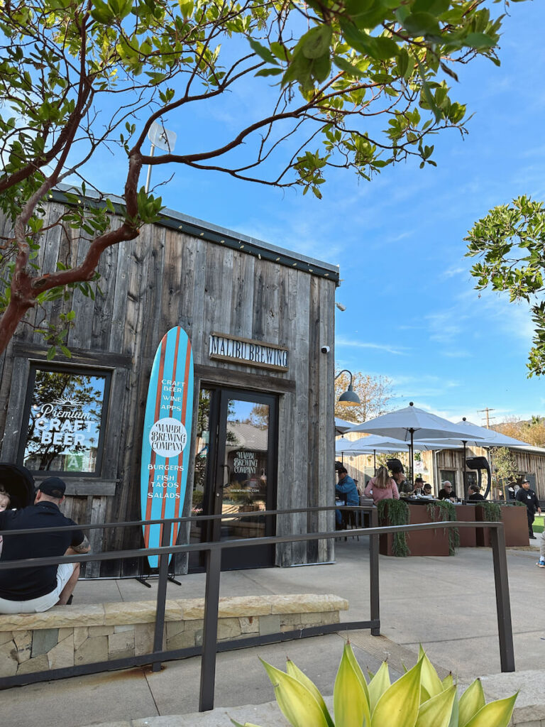 The exterior of Malibu Brewing Company, which has a blue surfboard on the left side of the door.