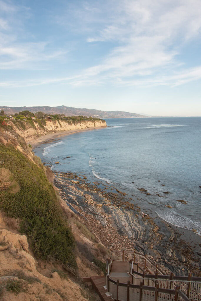 Stairs leading down to a beach, with a sweeping view of the coast.