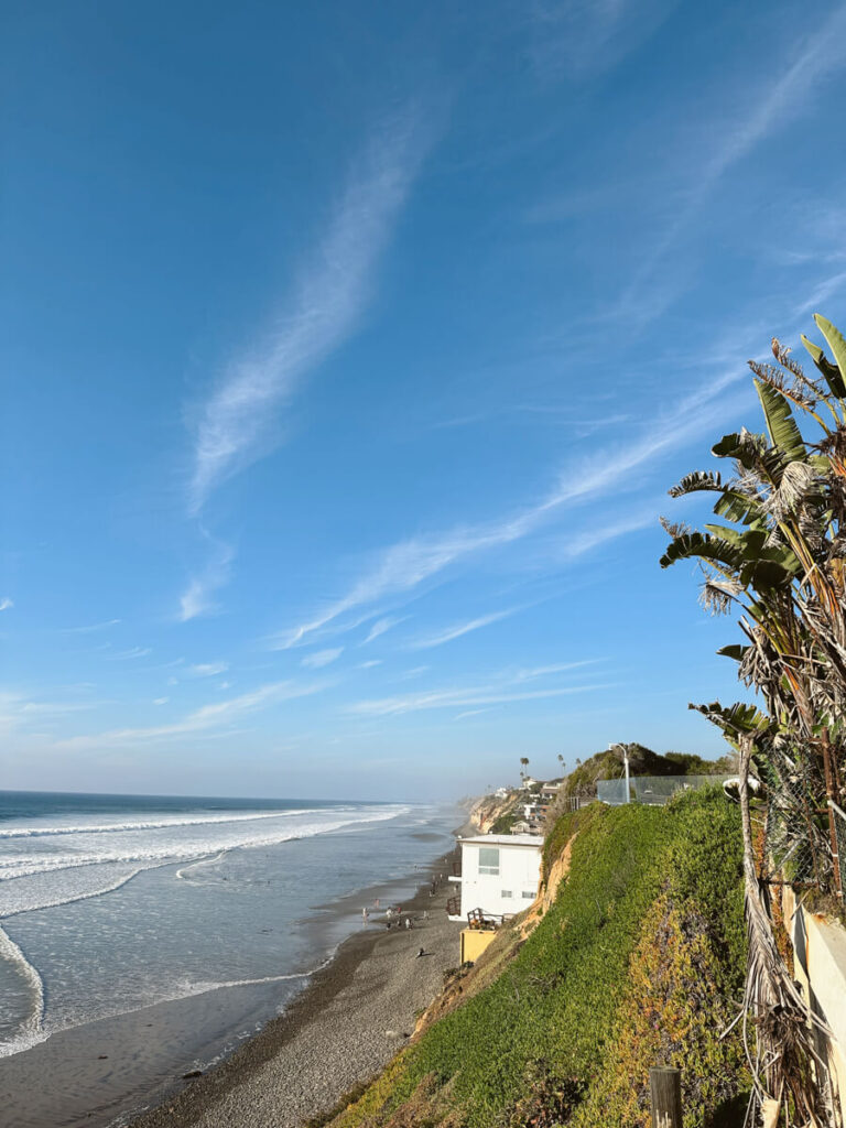 The view of the coastline from a viewpoint in Encinitas. The ocean is to the left, and there is a building on the coastal cliff on the right.