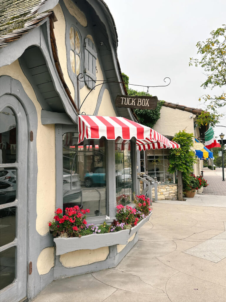 A cottage-style building with a red striped awning in Carmel