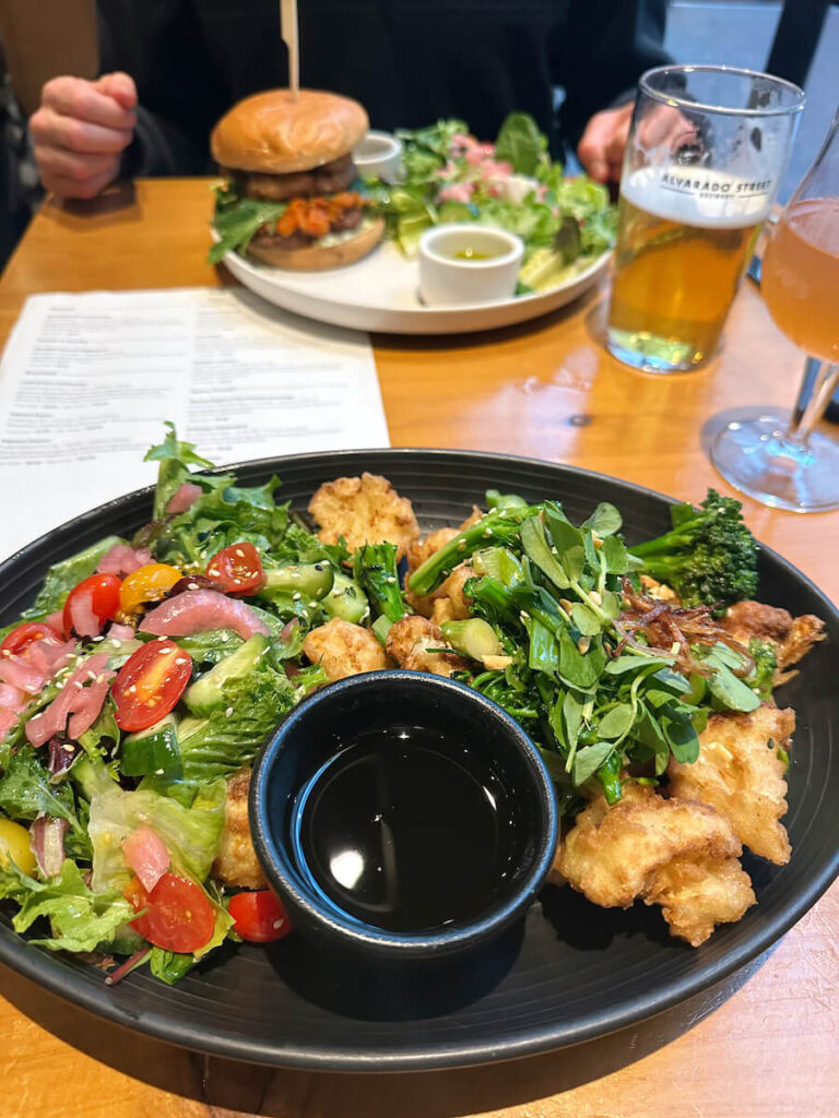 Two plates of food and two beers on a table at Alvarado Street Brewery. 