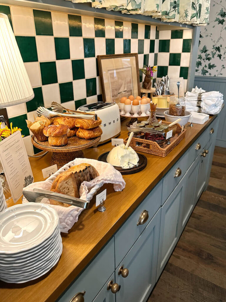 A breakfast spread on a bar with pastries, bread, hardboiled eggs, and yogurt