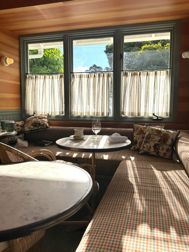 A dining nook with a long cushioned bench and three round tables