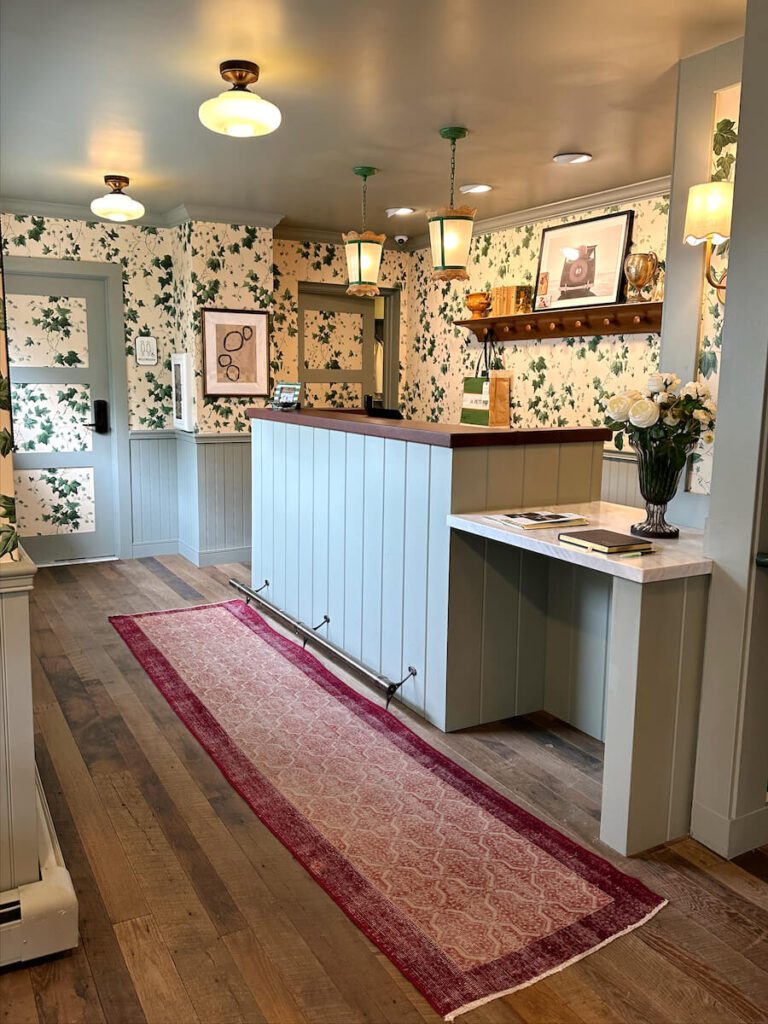 A red runner rug in front of a light green check in desk at Le Petit Pali