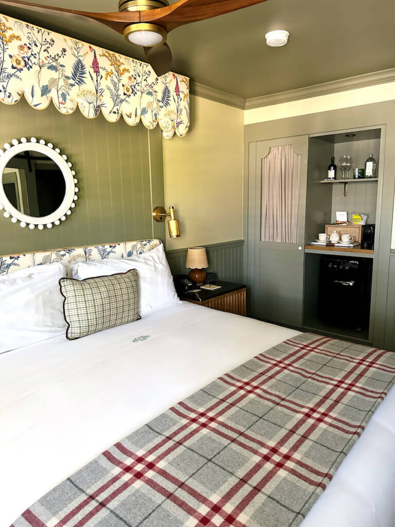 A bed with a floral headboard and round mirror hanging above it