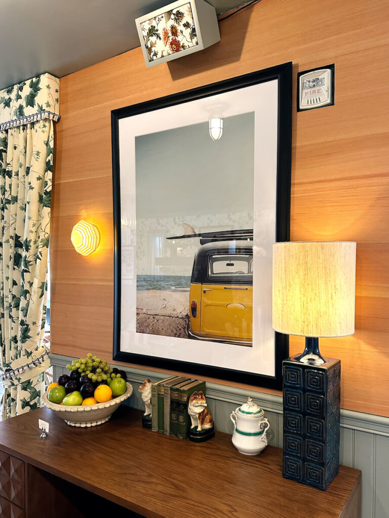 A photograph of a surfboard on top of a van on a wood paneled wall