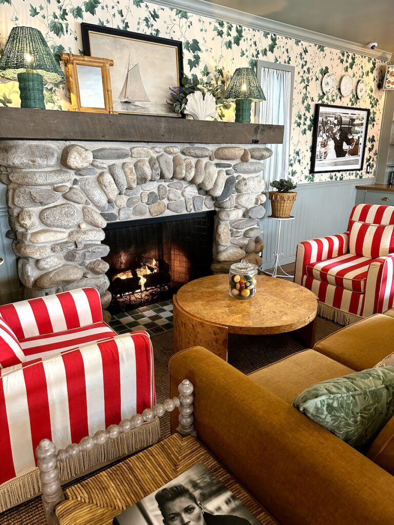 A brown couch and two red striped chairs in front of a stone fireplace