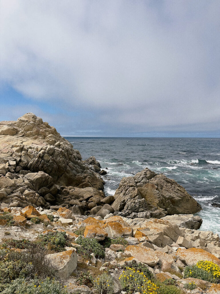 Rocks leading up to a large boulder in the ocean water on the left