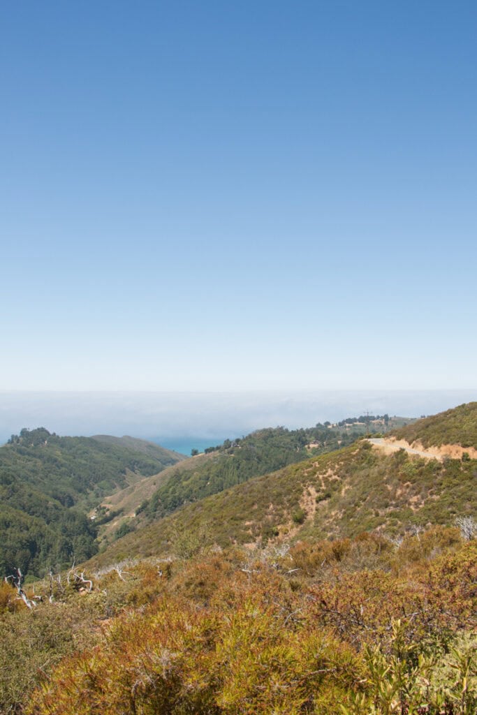 The view from the top of Buzzard's Roost of mountains and a sliver of ocean underneath fog visible in the distance