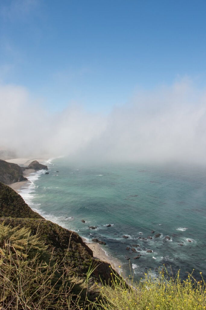 Looking out at the Big Sur coast from the Great Sur Vista Point. There is fog above the water and beach, but clear blue skies above it