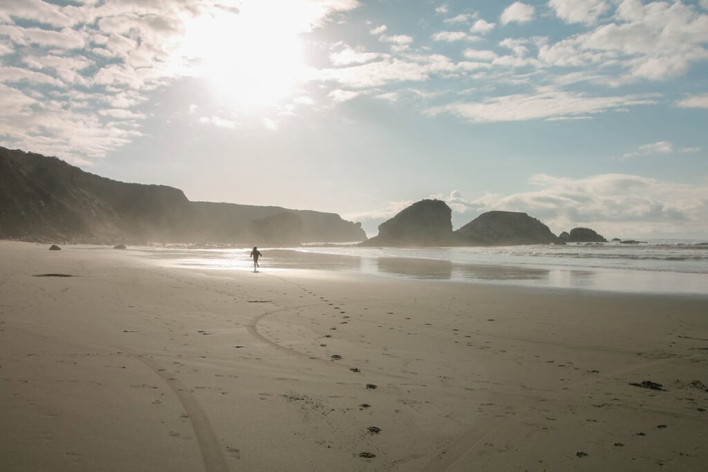 A woman running away from the camera on the beach at Sand Dollar Beach