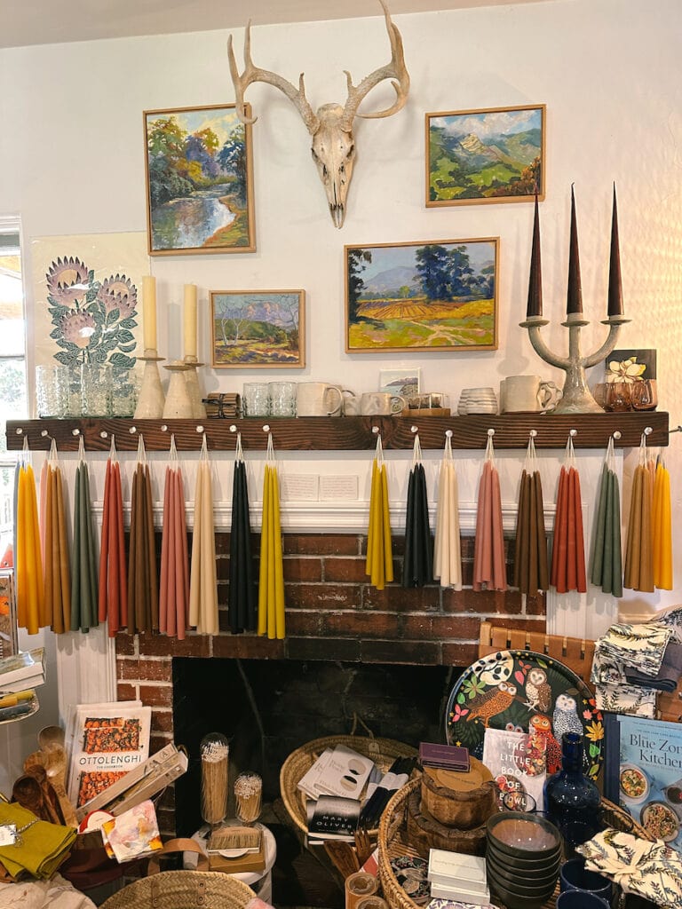 The Bungalow shop in Ojai. A variety of different colored taper candles hanging from a beam, with different home goods for sale around them. 