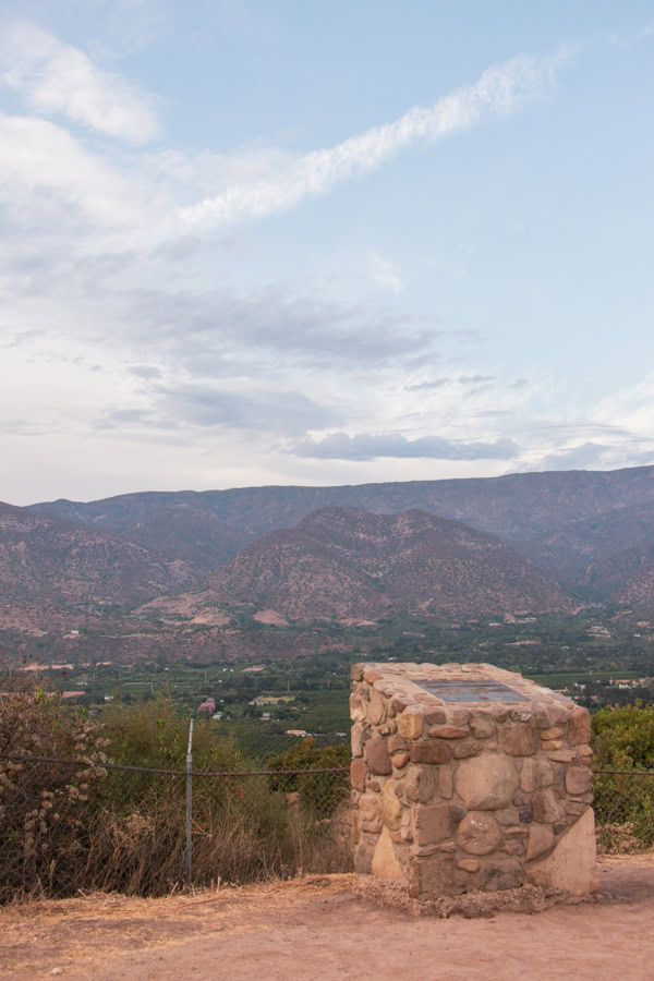 A view overlooking the Ojai Valley and Topa Mountains from the scenic point. There is a stone placard in the foreground.