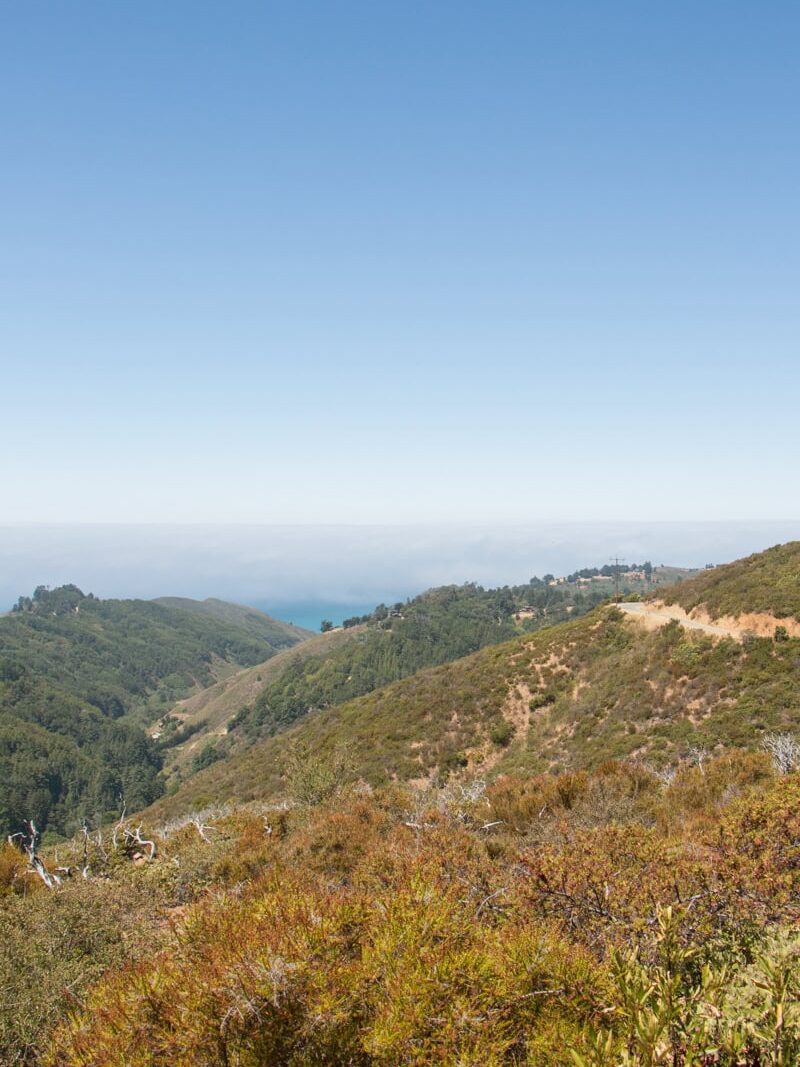 The view from the top of Buzzard's Roost of mountains and a sliver of ocean underneath fog visible in the distance