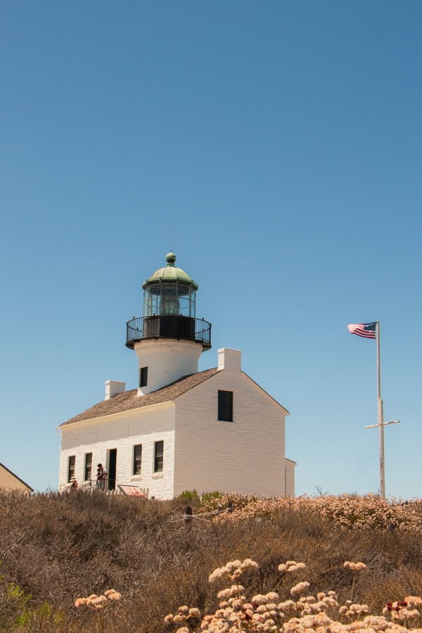 The white stone lighthouse at Cabrillo National Monument, next to a flag pole with the American flag