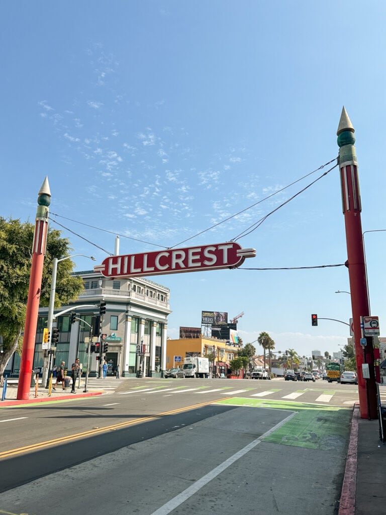 A red and white sign that reads "Hillcrest" suspended over the road