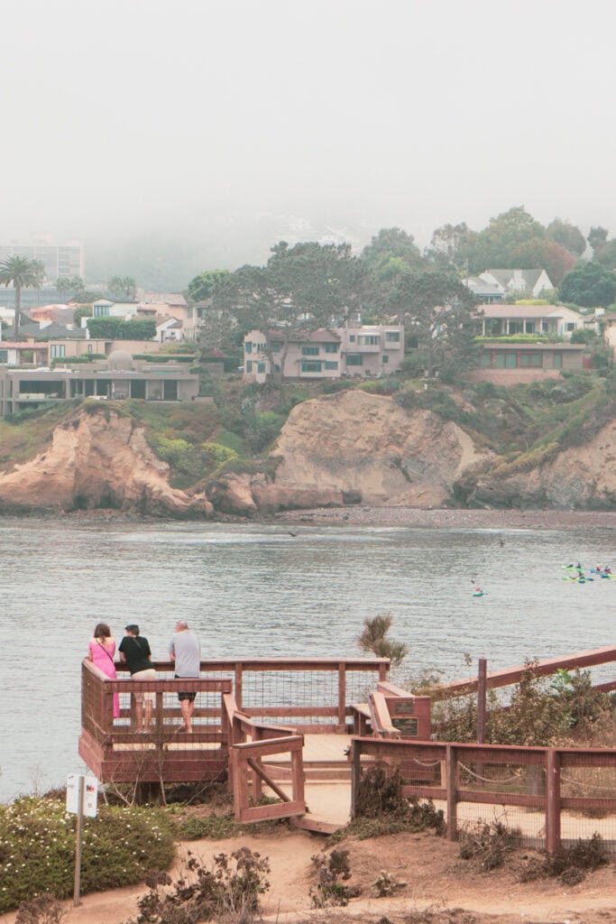 Three people standing on an observation deck looking over the water on the Coastal Trail in La Jolla