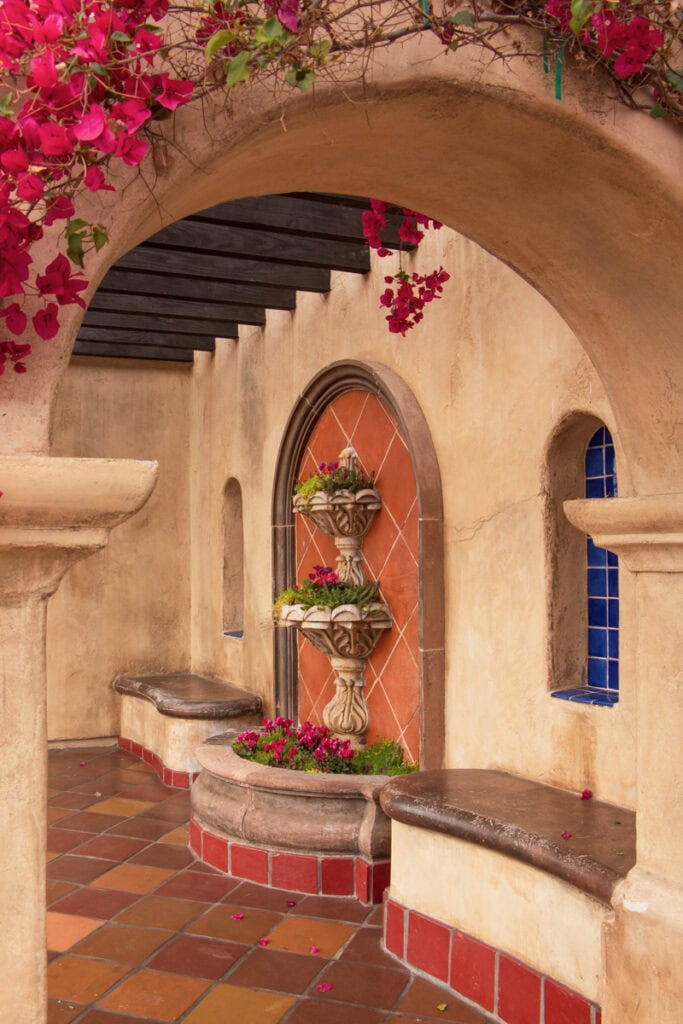 Pink flowers in front of an arch and a fountain in Old Town