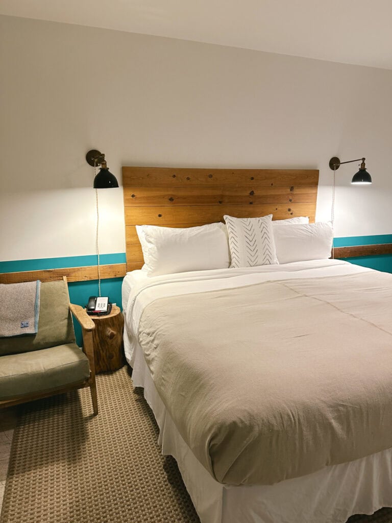 A bed with a wooden headboard and a chair to the left. 