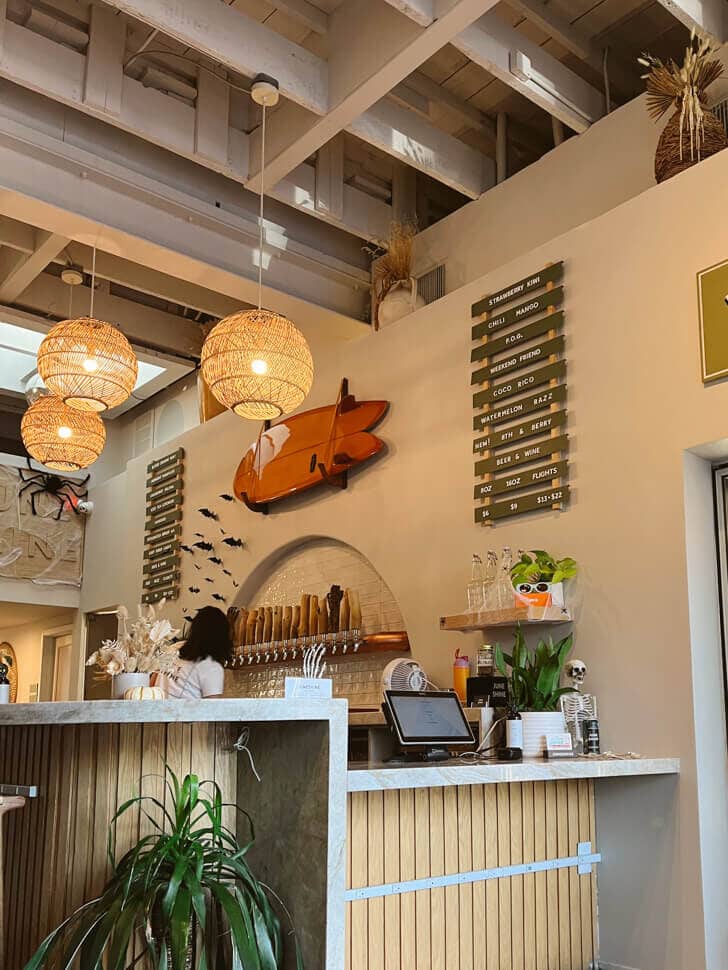 The bar at JuneShine. There are rattan lamps hanging over the bar, and kombucha taps behind the bar