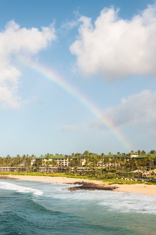 A rainbow over Shipwreck Beach and a beachside hotel