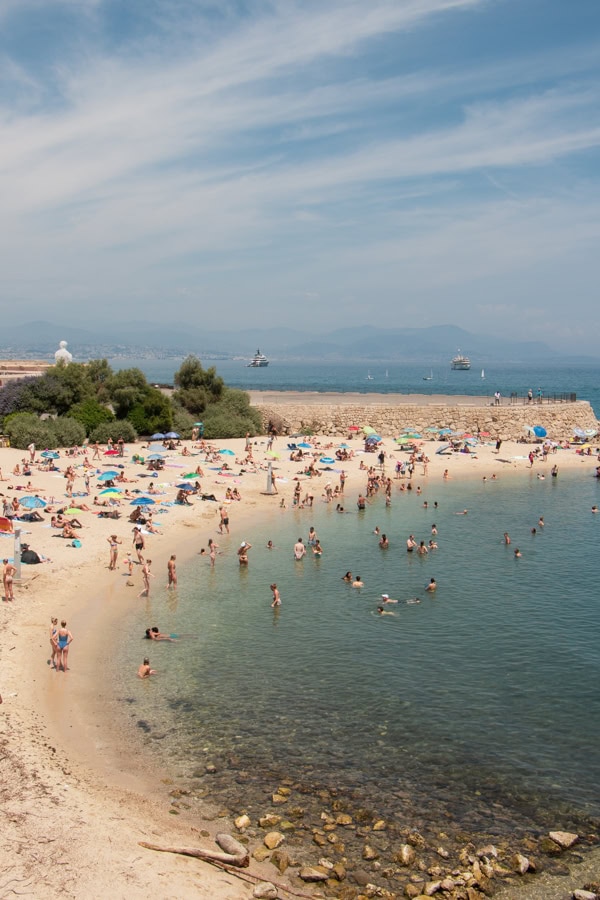 A view of Plage de Gravette from the Ramparts. It is a busy cove beach with people in the water and on the sand