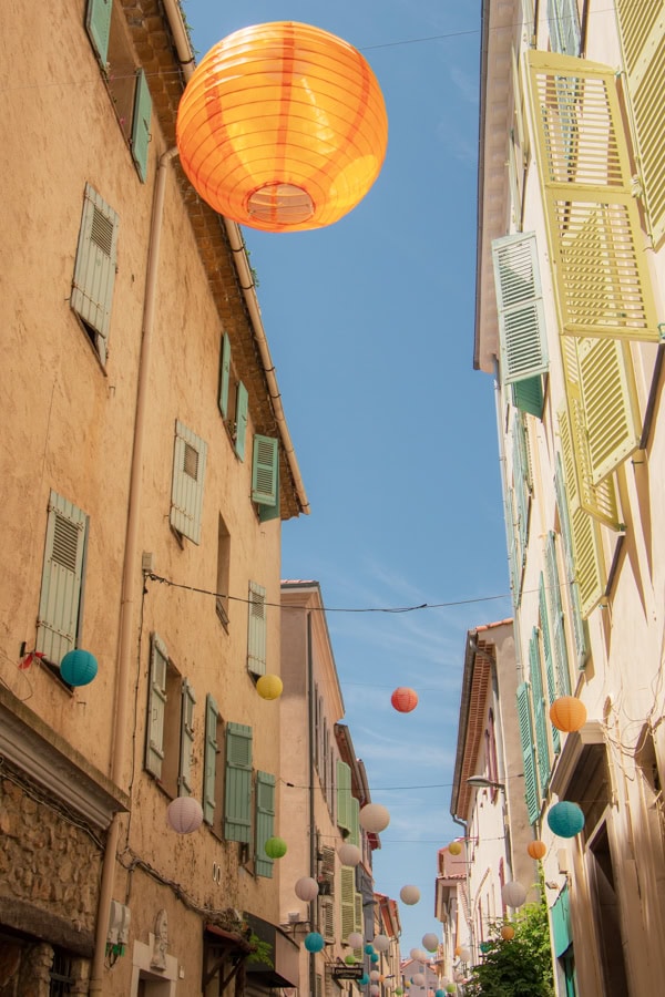 Multi-colored paper lanterns hanging across a walkway in Antibes
