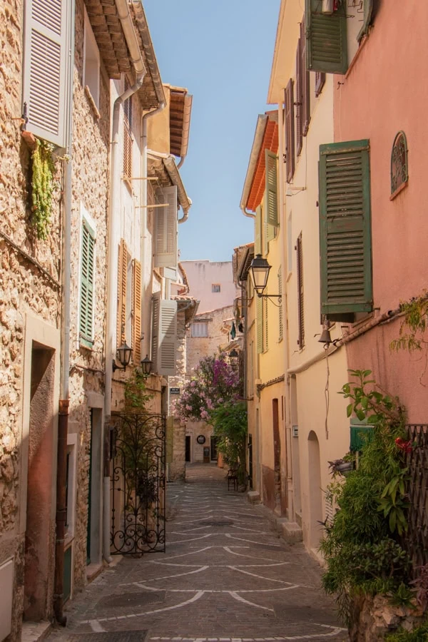 A narrow stone passageway lined by stone and pastel-colored buildings in Antibes