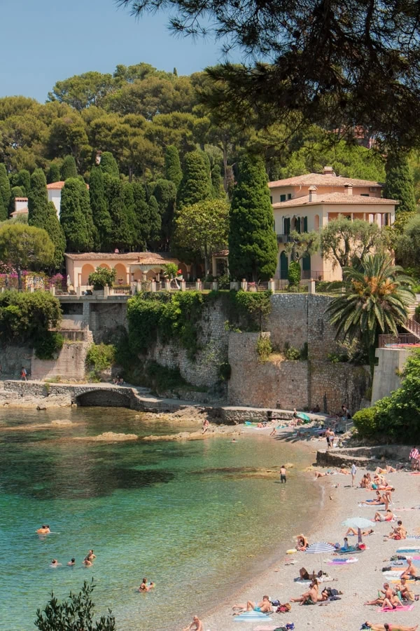 Beach goers lounging at Paloma Beach. There is a villa situated on the cliff above the beach.