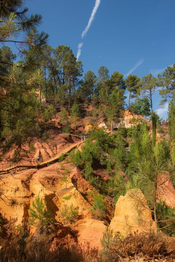 Stairs leading down the orange ochre cliffs in Roussillon. The cliffs are dotted with trees