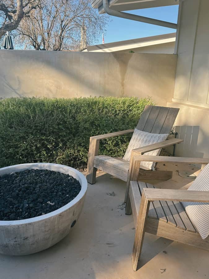 Two wooden lounge chairs by a fire pit at the private patio outside a room at Hotel Ynez