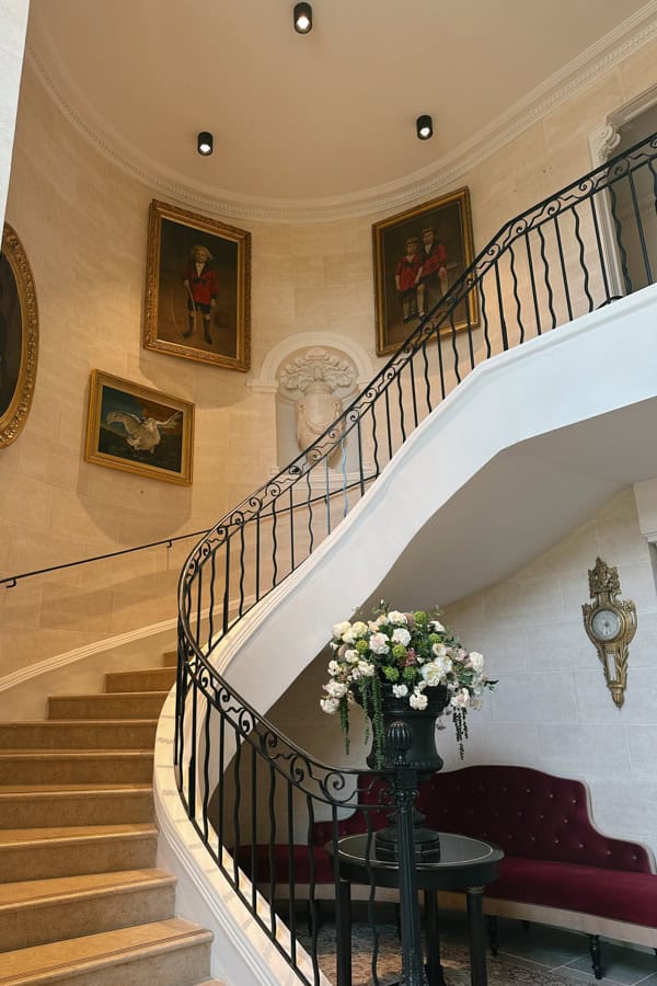 A curved staircase at Villa Saint-Ange. There are paintings on the wall along the staircase