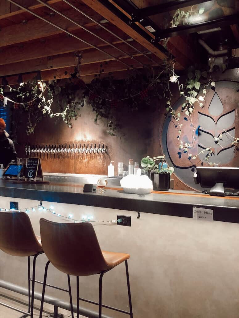 Two bar stools against the bar at and beer taps behind the bar at Pure Project Brewery in Carlsbad, CA