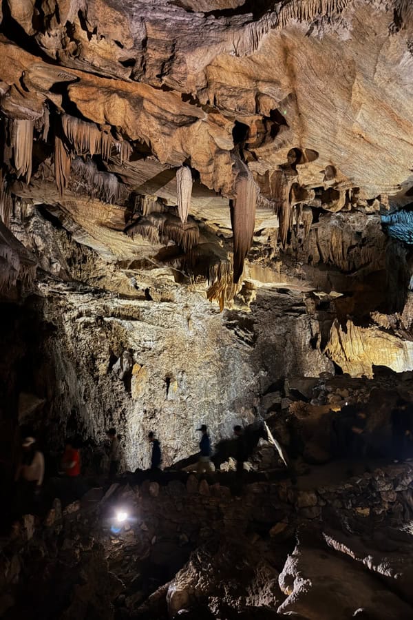 The interior of one of the rooms on the Crystal Cave tour in Sequoia. There are stalactites coming down from the ceiling, and people on the walking path below.